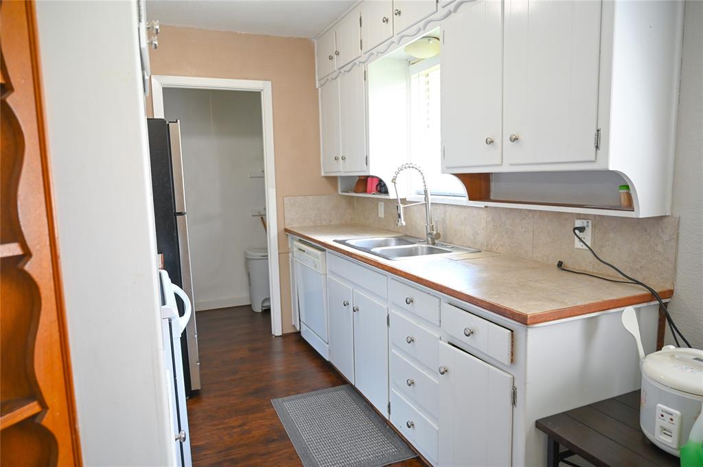 1352 Simpson Drive Hurst, TX 76053 - Photo 25 of 40 Kitchen featuring white cabinetry, wood-finish flooring, a double basin stainless steel sink, and a tiled backsplash
