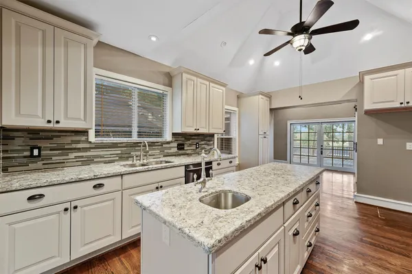 a kitchen with granite countertop a sink a counter space appliances and cabinets