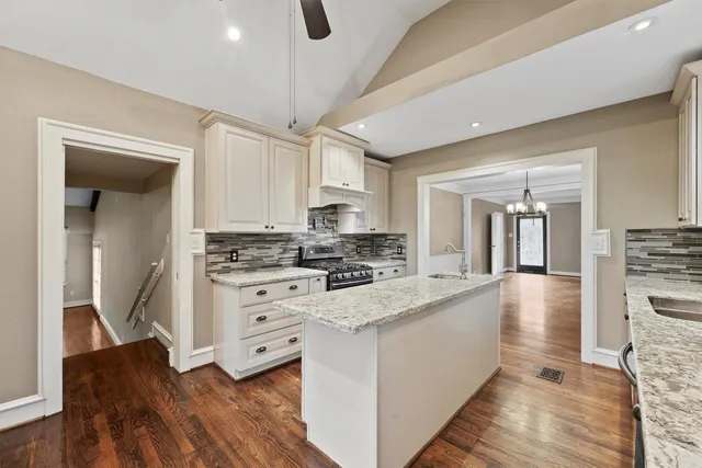 a kitchen with stainless steel appliances granite countertop a stove and white cabinets