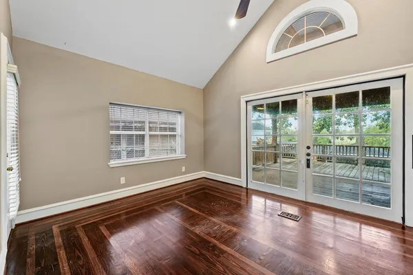 a view of empty room with wooden floor and fan