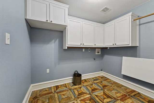 a kitchen with white cabinets and wooden floor