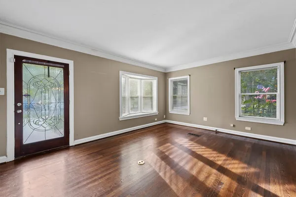 a view of an empty room with window and wooden floor