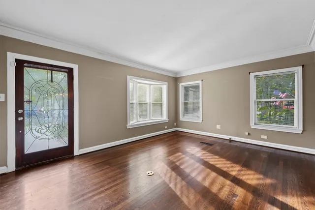 a view of an empty room with window and wooden floor