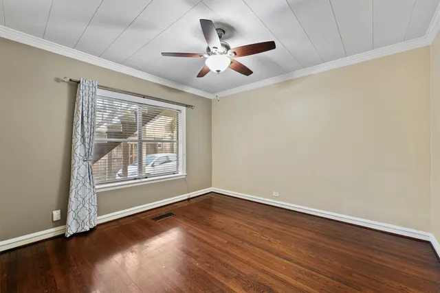 an empty room with wooden floor chandelier fan and windows
