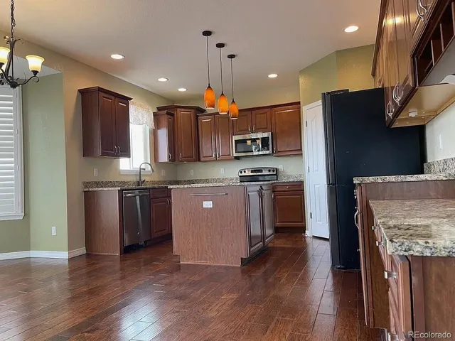 a kitchen with kitchen island granite countertop wooden floors stainless steel appliances a sink and a counter top