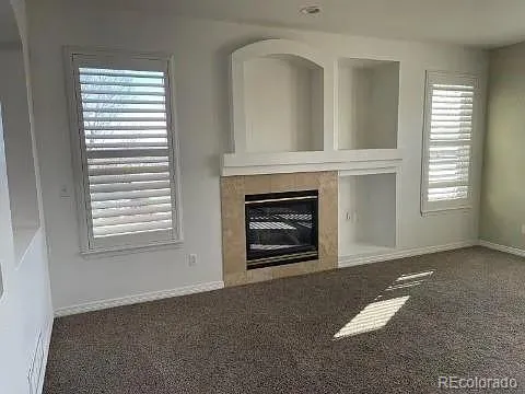 an empty room with windows fireplace and sink