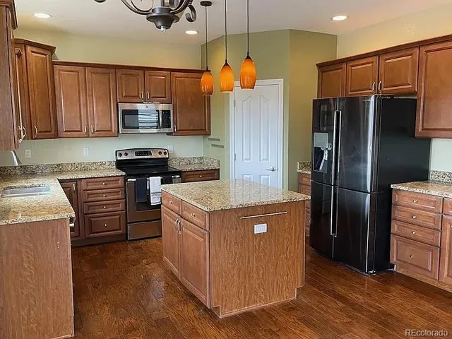 a kitchen with stainless steel appliances granite countertop a stove top oven a refrigerator and cabinets