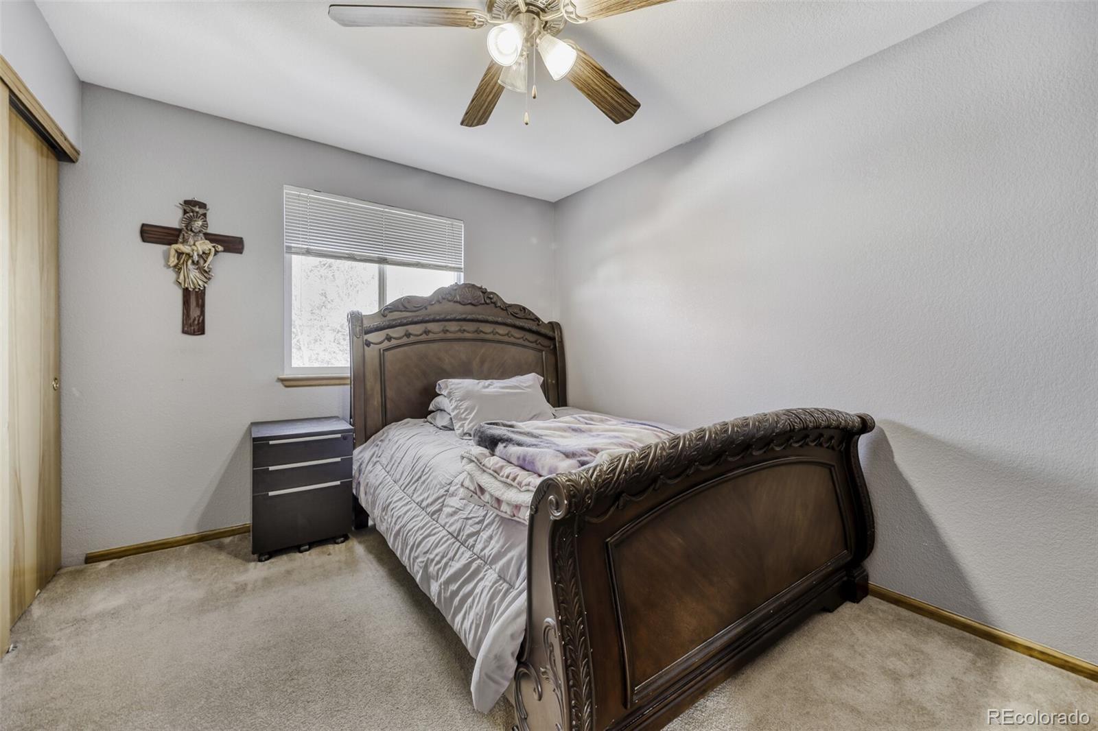 1435 Hummingbird Circle Brighton, CO 80601 - Photo 13 of 22 a bedroom with a bed and ceiling fan
