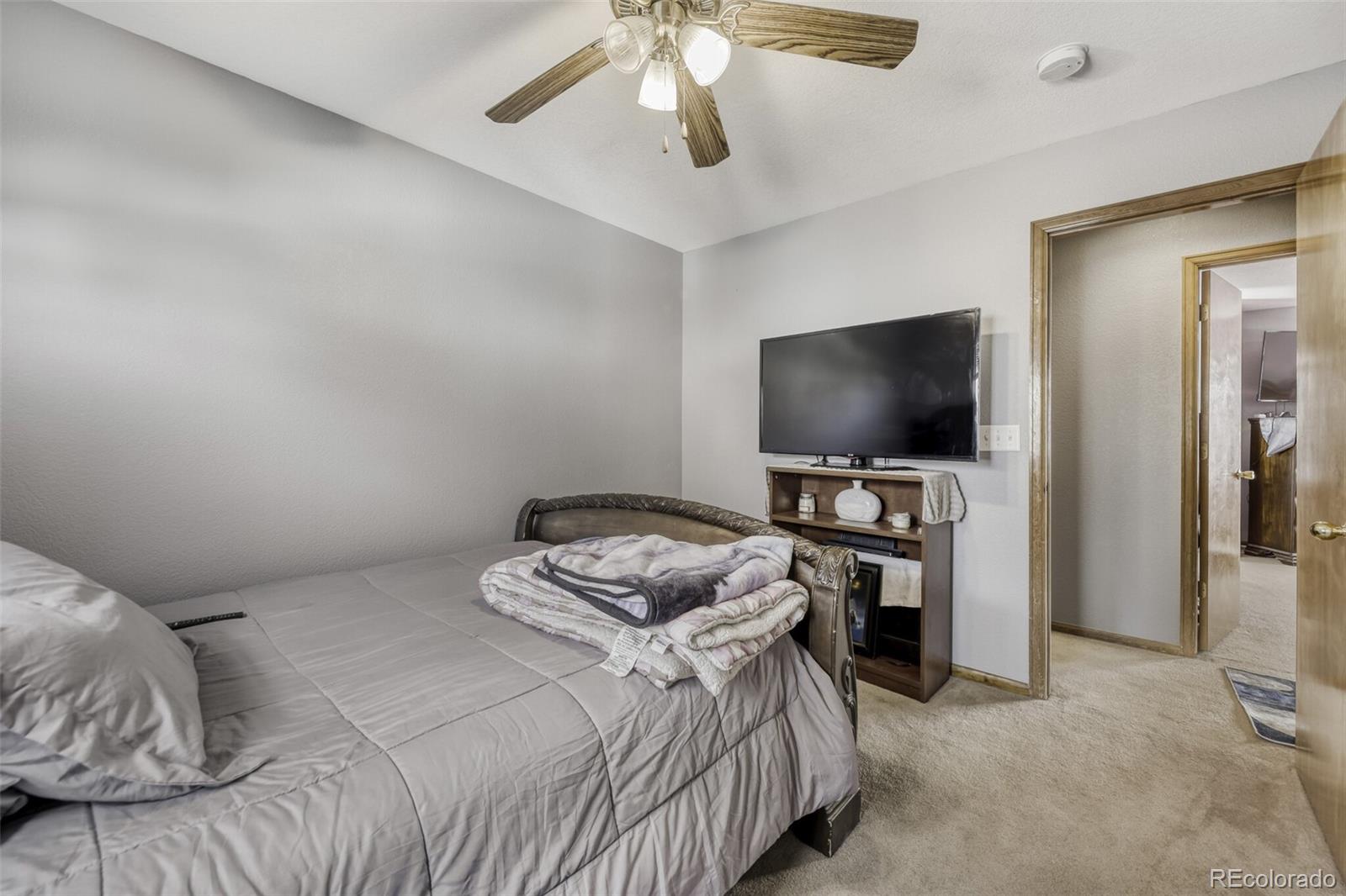 1435 Hummingbird Circle Brighton, CO 80601 - Photo 14 of 22 a bedroom with a bed and a flat tv screen on wall