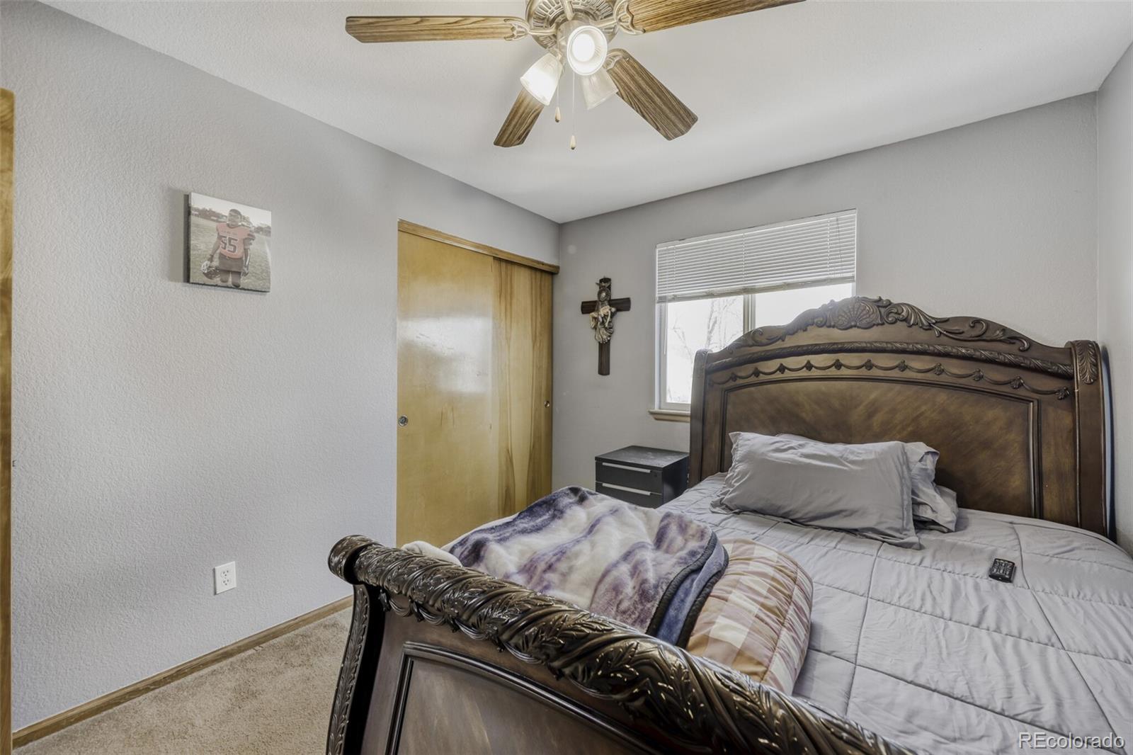 1435 Hummingbird Circle Brighton, CO 80601 - Photo 15 of 22 a bedroom with a bed and a chandelier