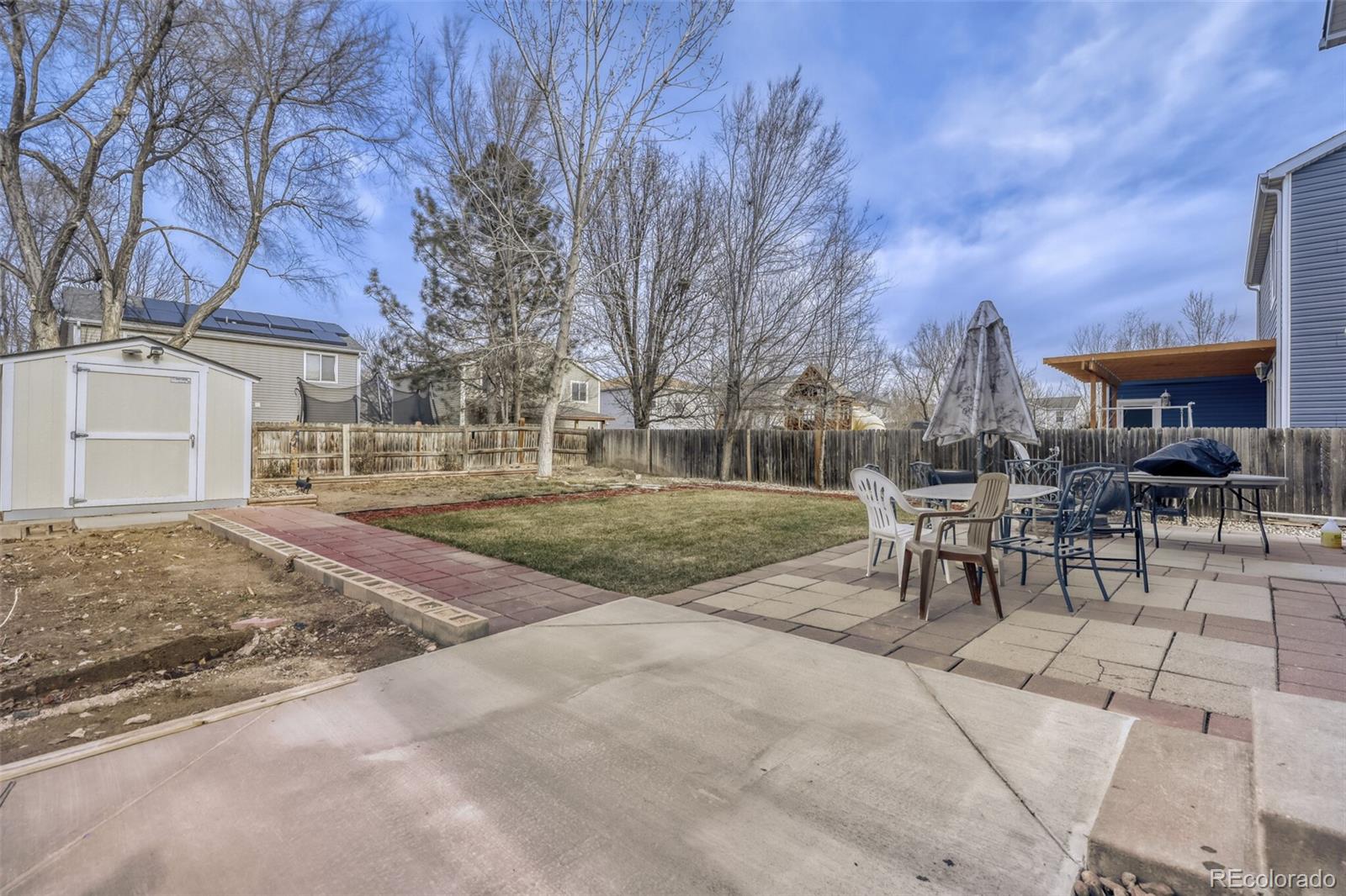 1435 Hummingbird Circle Brighton, CO 80601 - Photo 20 of 22 a view of a backyard with table and chairs and a fire pit