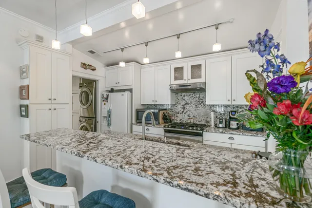 a kitchen with granite countertop a stove a sink and a refrigerator