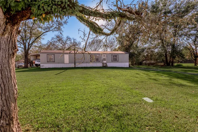 a view of a house with a big yard and large trees