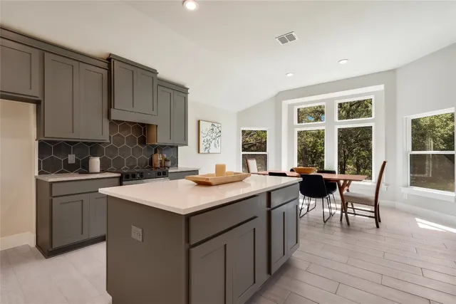 a kitchen with a stove a sink a kitchen island with a dining table and chairs