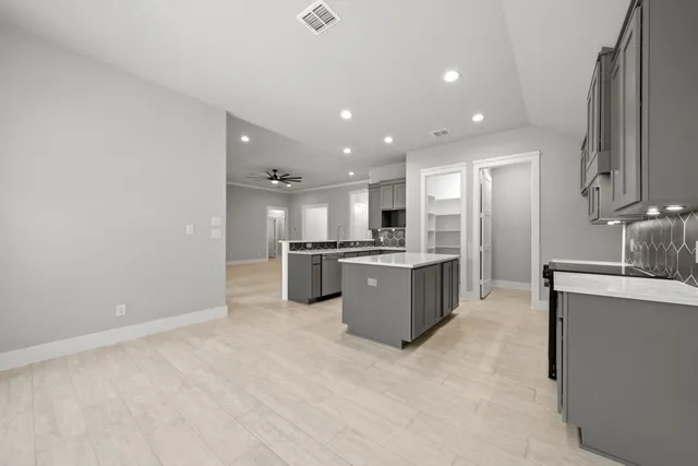 a large kitchen with a large counter top a sink stainless steel appliances and cabinets