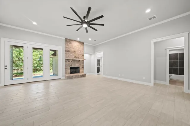 an empty room with windows fireplace and a ceiling fan