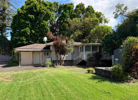 a front view of a house with a yard and tree