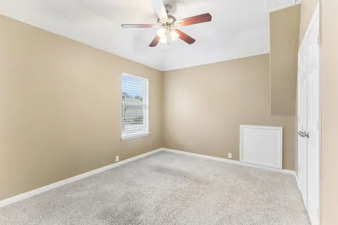 an empty room with windows and fan
