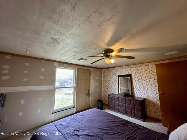 a bedroom with a bed window and mirror