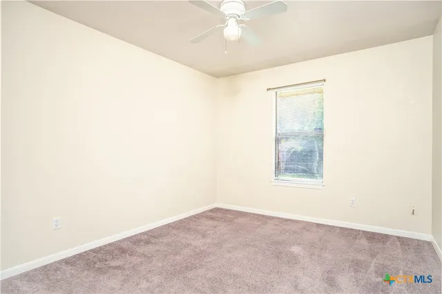 an empty room with a fan & a window