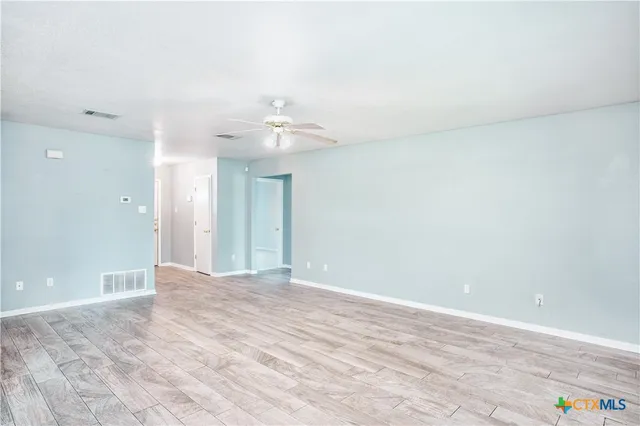 a view of an empty room with a chandelier fan