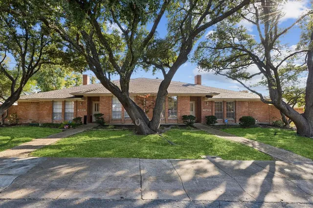 a front view of a house with a garden and trees