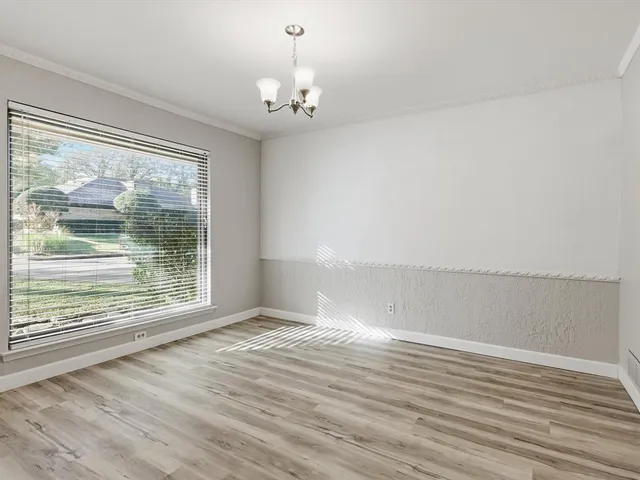 a view of an empty room with wooden floor and a ceiling fan