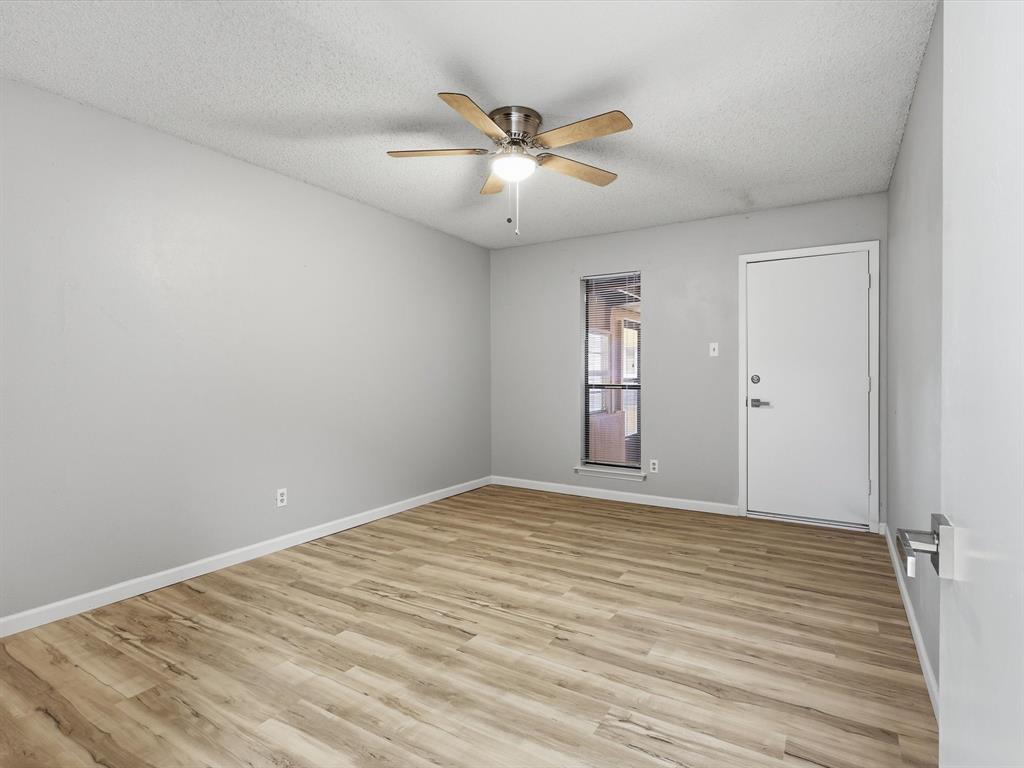 1811 Briarcrest Lane Arlington, TX 76012 - Photo 19 of 29 a view of an empty room with wooden floor and a ceiling fan