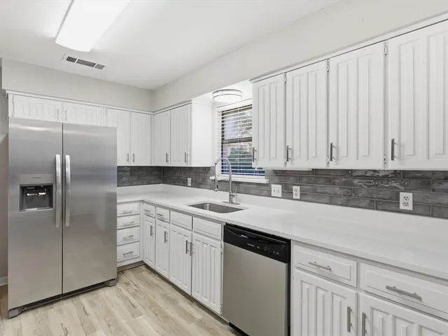 a kitchen with cabinets stainless steel appliances and wooden floor