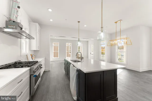 a kitchen with stainless steel appliances kitchen island granite countertop a sink a stove and a wooden floors