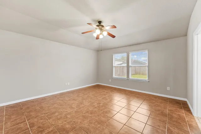a view of an empty room with window and chandelier fan