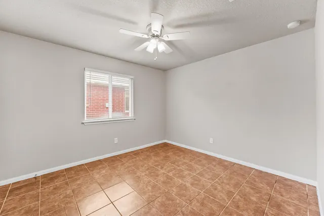 an empty room with a chandelier fan and windows