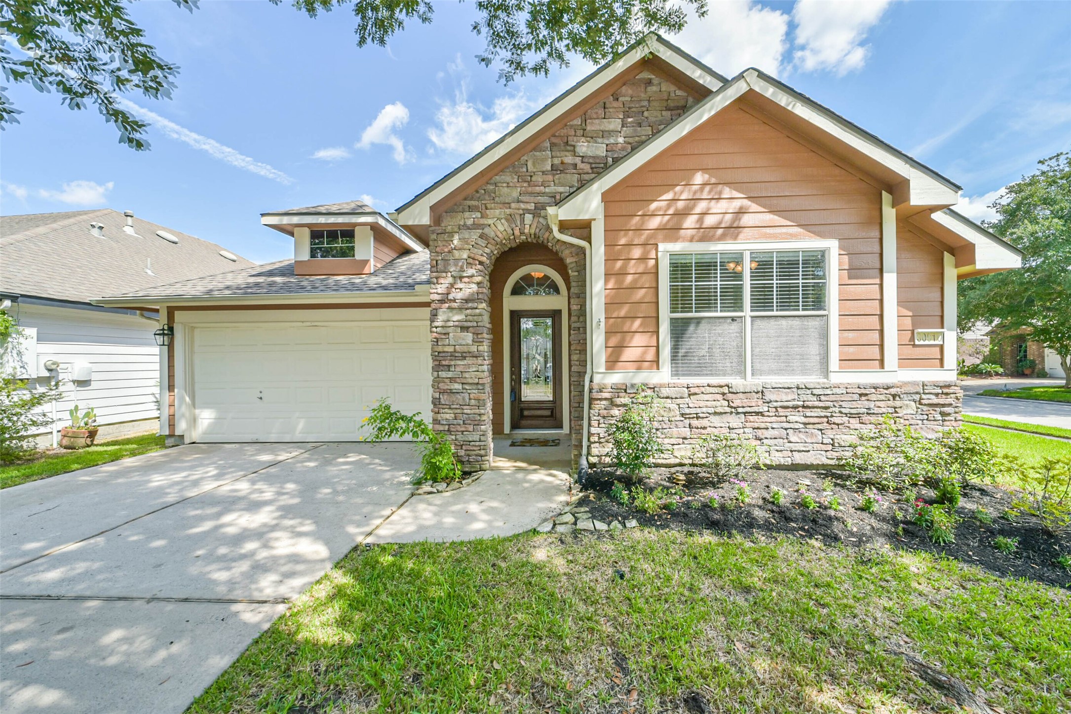 30910 Blue Ridge Park Lane Spring, TX 77386 - Photo 49 of 50 Charming home with a blend of stone and siding exterior, featuring a welcoming arched entryway and a spacious two-car garage. Lush landscaping enhances its curb appeal.