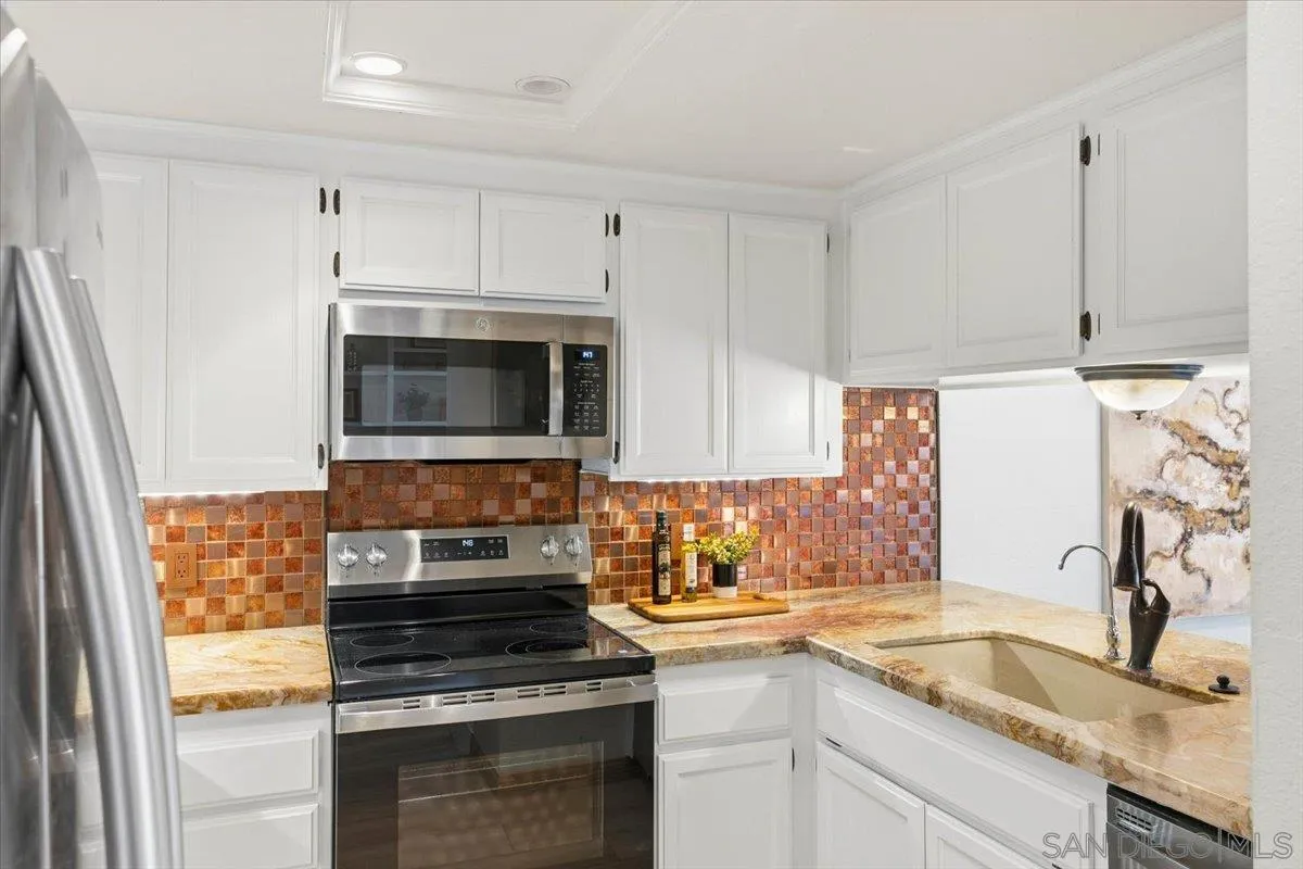 2630 Pirineos Way, Unit 5 Carlsbad, CA 92009 - Photo 12 of 48 a kitchen with granite countertop a stove sink and microwave
