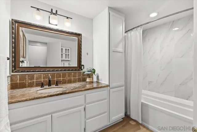 a bathroom with a granite countertop sink a mirror and a bathtub