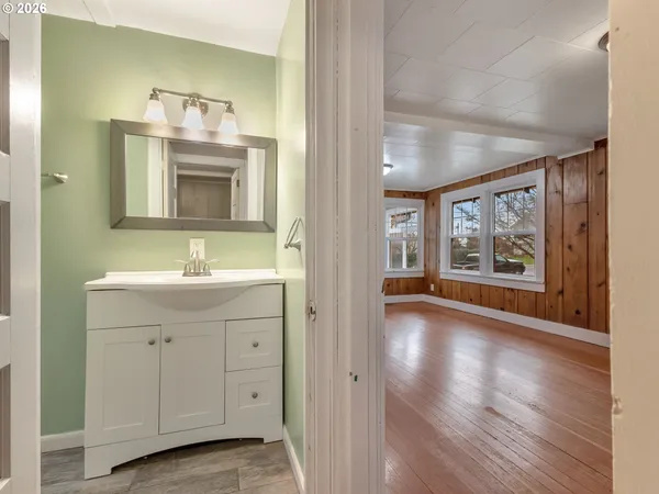a view of an empty room with window and wooden floor