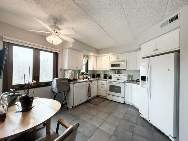 a kitchen with a refrigerator a stove a sink dishwasher with a dining table and chairs