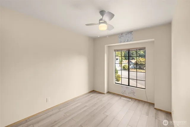 an empty room with wooden floor chandelier and windows