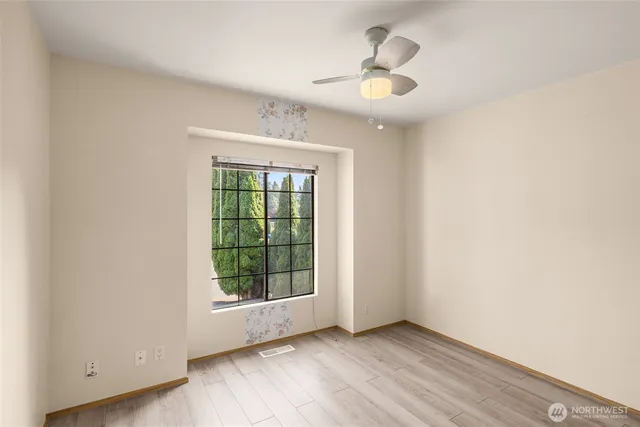an empty room with wooden floor chandelier fan and windows