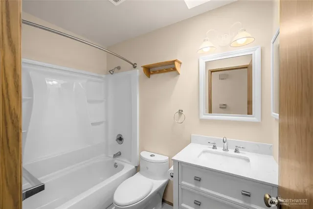 a bathroom with a toilet a sink a mirror a bathtub and vanity