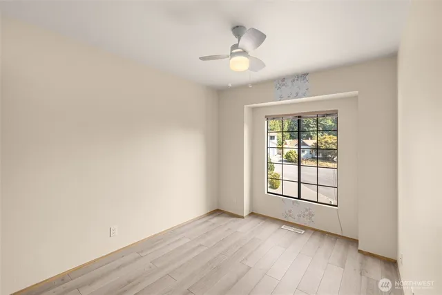 an empty room with wooden floor chandelier and windows