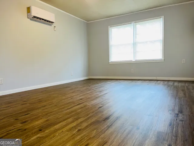 a view of an empty room with wooden floor and a window
