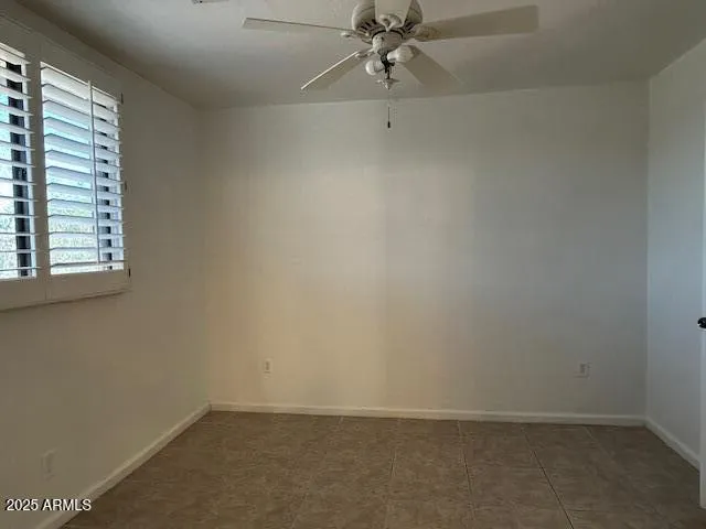 an empty room with a window and a fan