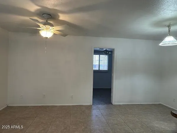 an empty room with windows and fan