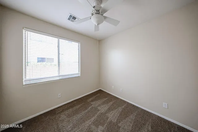 an empty room with a window and a ceiling fan