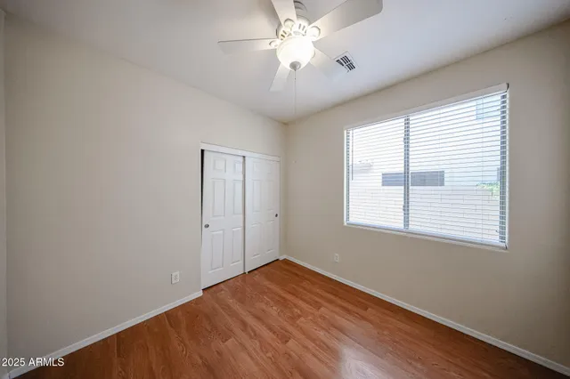 a view of empty room with wooden floor and fan