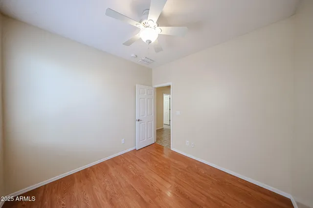 an empty room with a ceiling fan and wooden floor
