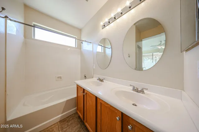 a bathroom with a double vanity sink mirror and a bathtub