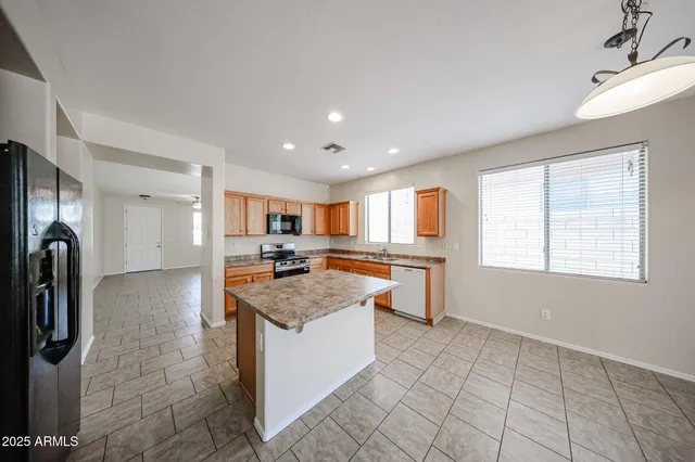 a kitchen with stainless steel appliances granite countertop a refrigerator a sink dishwasher and a stove with wooden floor