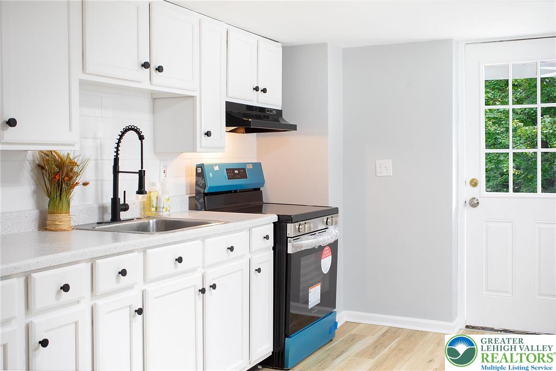 910 Butler Street Easton, PA 18042 - Photo 9 of 29 a kitchen with granite countertop white cabinets and a wooden floor